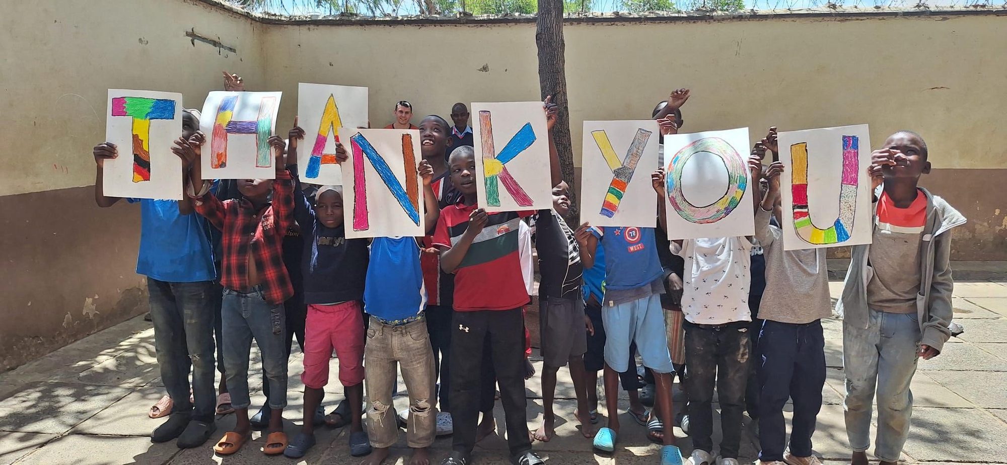 Kinder halten bunt gemalte Buchstaben und zeigen gemeinsam das Wort Thank you